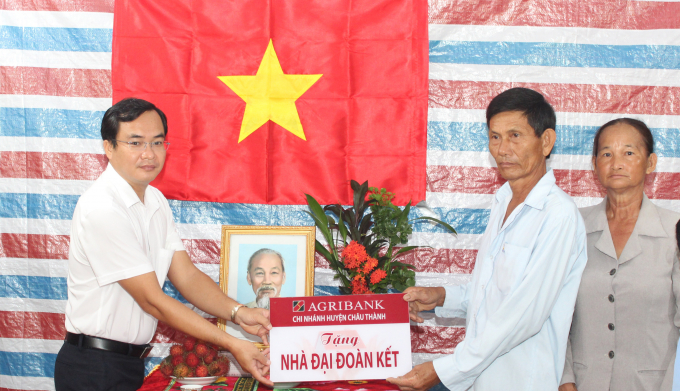 Ông Huỳnh Văn Huyền (bên trái), Giám đốc Agribank huyện Châu Thành, trao bảng tượng trưng cho gia đình ông Huỳnh Văn Paul. Ảnh: Quốc Trí.