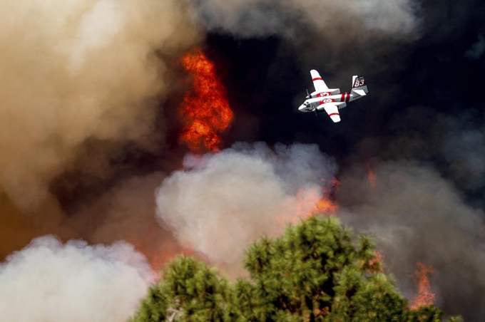 An air tanker flies past flames while battling the Oak Fire in Mariposa County, Calif., Sunday, July 24, 2022. Wildfires, floods and soaring temperatures have made climate change real to many Americans. Yet a sizeable number continue to dismiss the scientific consensus that human activity is to blame. That's in part because of a decades-long campaign by fossil fuel companies to muddy the facts and promote fringe explanations. Photo: AP