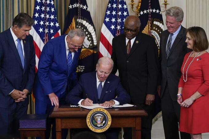 President Joe Biden signs the Democrats' landmark climate change and health care bill in the State Dining Room of the White House in Washington, Tuesday, Aug. 16, 2022, as from left, Sen. Joe Manchin, D-W.Va., Senate Majority Leader Chuck Schumer of N.Y., House Majority Whip Rep. James Clyburn, D-S.C., Rep. Frank Pallone, D-N.J., and Rep. Kathy Castor, D-Fla., watch. Photo: AP