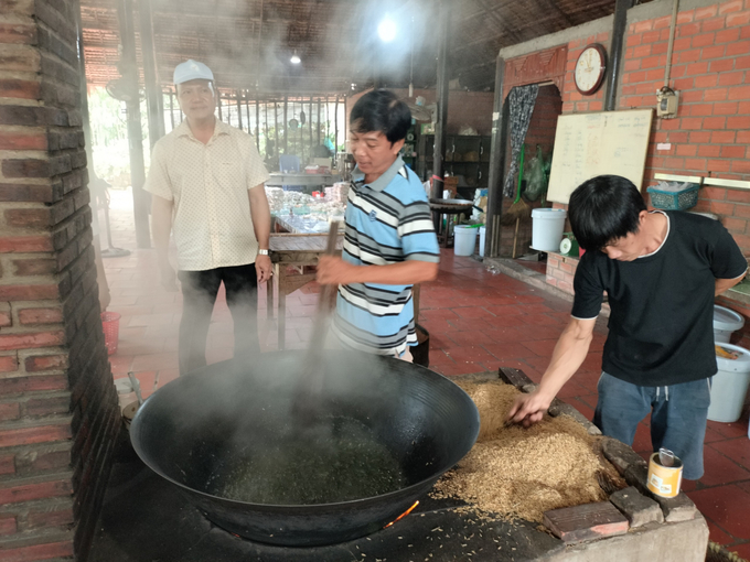Visitors observing green rice popping at a traditional green rice factory in An Binh island. Photo: Minh Dam.