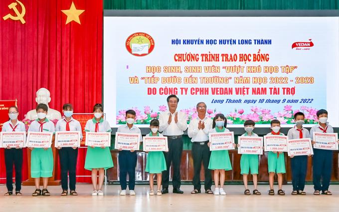 Ông Dương Minh Dũng - Bí thư huyện ủy Long Thành (trái) và ông Lê Minh Hoàng - Phó Chủ tịch Hội khuyến học tỉnh Đồng Nai trao học bổng cho các em học sinh.