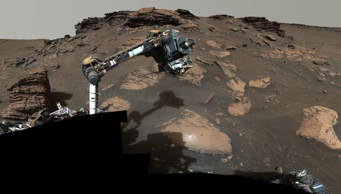 Robot tự hành Perseverance sử dụng cánh tay máy của mình thu thập mẫu vật quanh một mỏm đá trên Sao Hỏa. Ảnh: NASA.