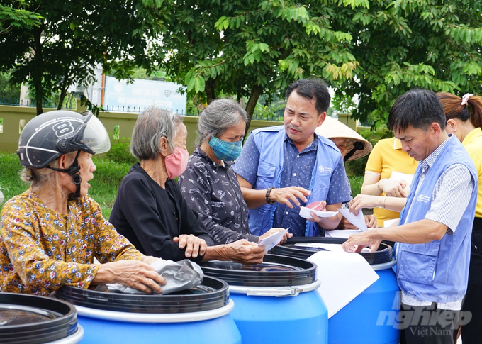 Người dân tỉnh Quảng Trị phấn khởi nhận thùng phuy và tiền hỗ trợ từ tổ chức FAO tại Việt Nam. Ảnh: Võ Dũng.