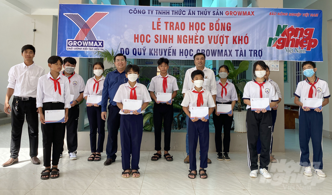 Ông Nguyễn Văn Dũng, quản lý khu vực Đông Nam bộ Công ty TNHH thức ăn thủy sản GrowMax (áo trắng - giữa) trao học bổng cho 10 học sinh Trường THCS Lộc An. Ảnh: Thiên Vương.