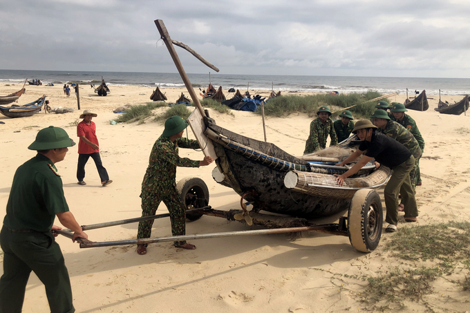 Tại các xã, huyện ven biển của tỉnh Quảng Trị, bộ đội biên phòng giúp dân thu ngư lưới cụ, vận chuyển tàu thuyền lên bờ tránh báo Noru. Ảnh: Đình Tiến.