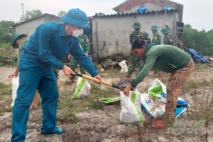 Bộ đội biên phòng, chính quyền địa phương xã Triệu An giúp đỡ gia đình chị Lê Thị Hoa chằng chống nhà cửa ứng phó bão Noru. Ảnh: Võ Dũng.