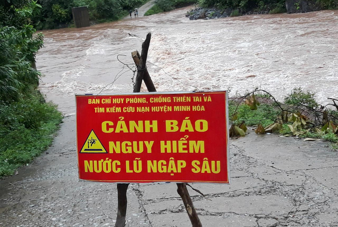 Cơ quan chức năng huyện Minh Hóa cắm biển cảnh báo nguy hiểm ở khu vực lũ ngập. Ảnh: Đ.T.