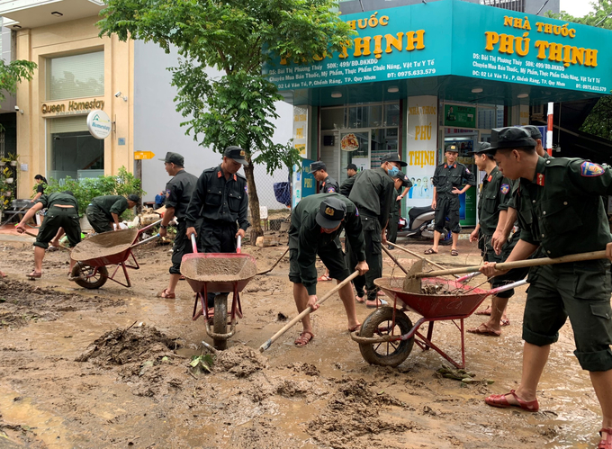 Bộ đội hốt bùn đất bám trên mặt đường tại phường Gềnh Ráng (TP.Quy Nhơn, Bình Định) do mưa lớn và nước từ núi Vũng Chua chảy xuống gây ngập trong đêm 11/10. Ảnh: .B.T.