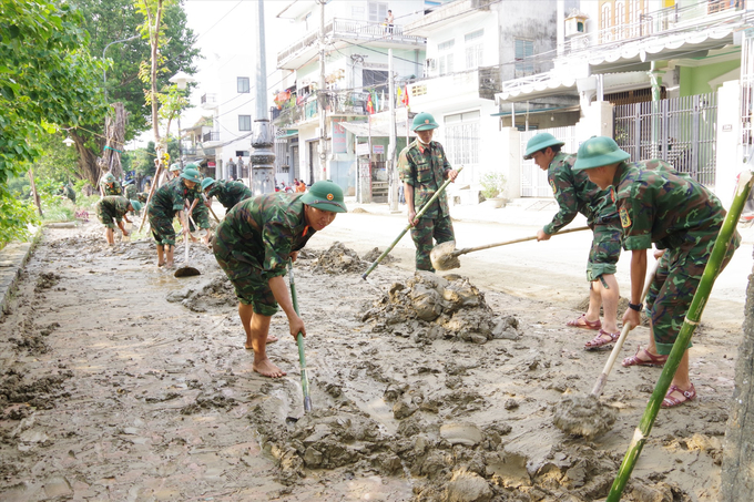 Lực lượng vũ trang giúp dân dọn dẹp bùn đất sót lại sau mưa lũ. Ảnh: Lao động.