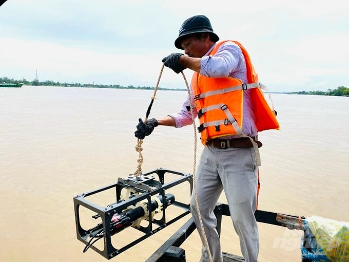 A measurement tool is dropped into the Hau River to calculate the annual amount of mud and sand. Photo: Le Hoang Vu.