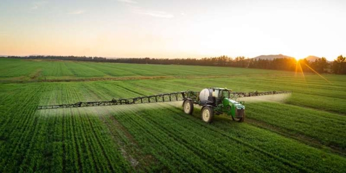 A farmer spray pesticides on crops.