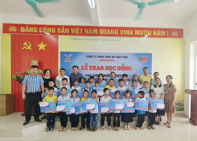Lãnh đạo Công ty GrowMax và PV Báo Nông nghiệp Việt Nam trao 25 suất học bổng đã được trao cho 25 em học sinh có hoàn cảnh khó khăn của trường Tiểu học Hợp Đức. Ảnh: MH.