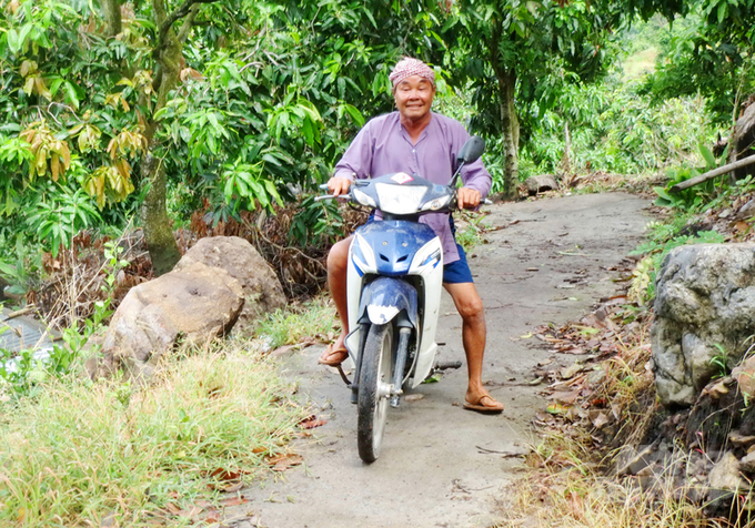 Từ khi có con đường bê tông dài 2,5km, hàng ngày ông Út Quít đều dùng xe gắn máy vận chuyển trái cây từ núi xuống đất rất thuận tiện. Ảnh: Lê Hoàng Vũ.
