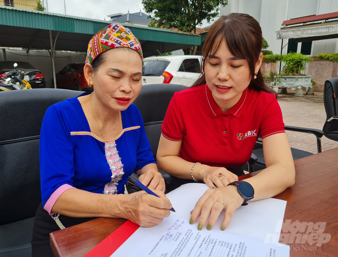 Nhân viên Bảo hiểm Agribank hướng dẫn thủ tục cho khách hàng Vi Thị Phiên. Ảnh: Việt Khánh.