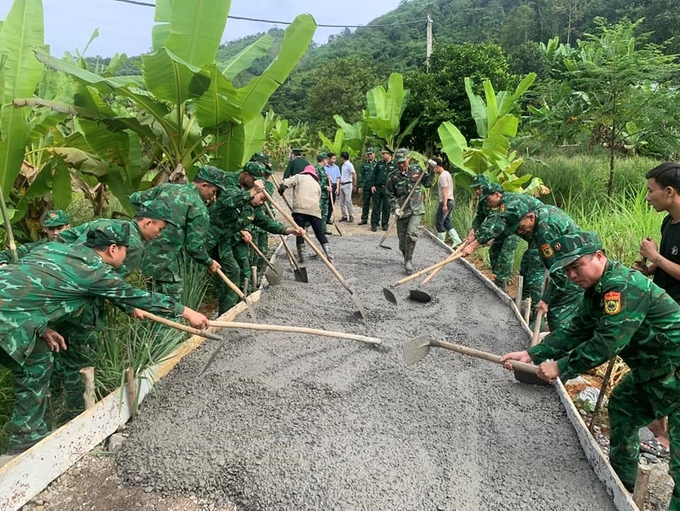 Bộ đội Biên phòng cùng người dân xã Bản Phiệt làm đường bê tông, xây dựng nông thôn mới. Ảnh: T.L