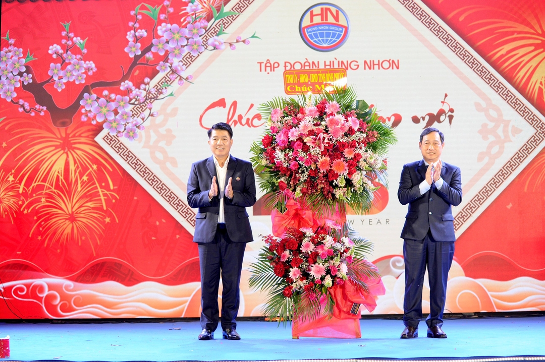 Ông Vũ Mạnh Hùng - Chủ tịch HĐQT kiêm Tổng Giám đốc Tập đoàn Hùng Nhơn (bên trái) nhận lãng hoa chúc mừng của Tỉnh ủy, HĐND, UBND tỉnh Bình Phước.