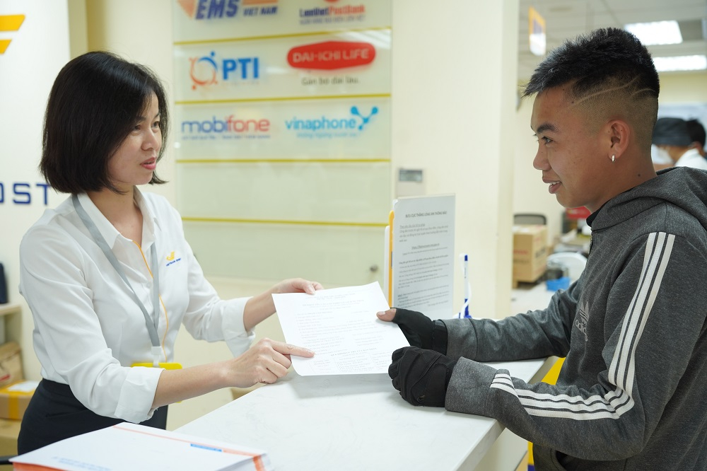 Nhân viên Bưu điện Việt Nam hướng dẫn khách hàng khai thông tin trên Cổng Dịch vụ công trực tuyến. Ảnh: Hoài Giang.