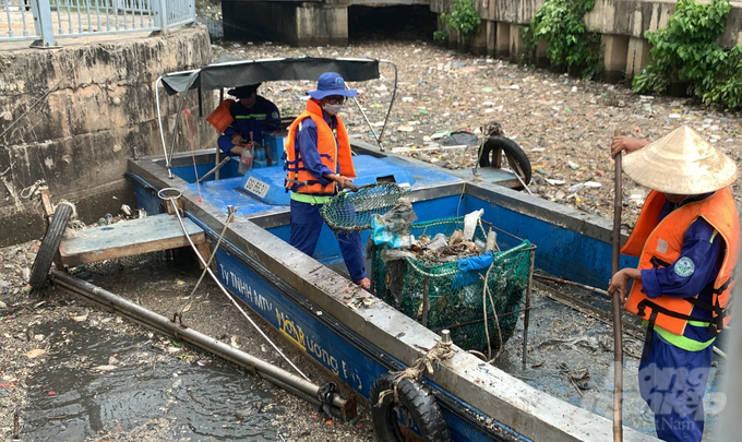 Công nhân Công ty Môi trường Đô thị TP. HCM đang khẩn trương thu gom rác và cá chết để tránh ảnh hưởng đến người dân và môi trường. Ảnh: Lê Bình.