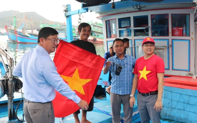 Những lá cờ được ngư dân mang ra tàu chuẩn bị treo lên để vươn khơi bám biển. Ảnh: Kim Sơ.