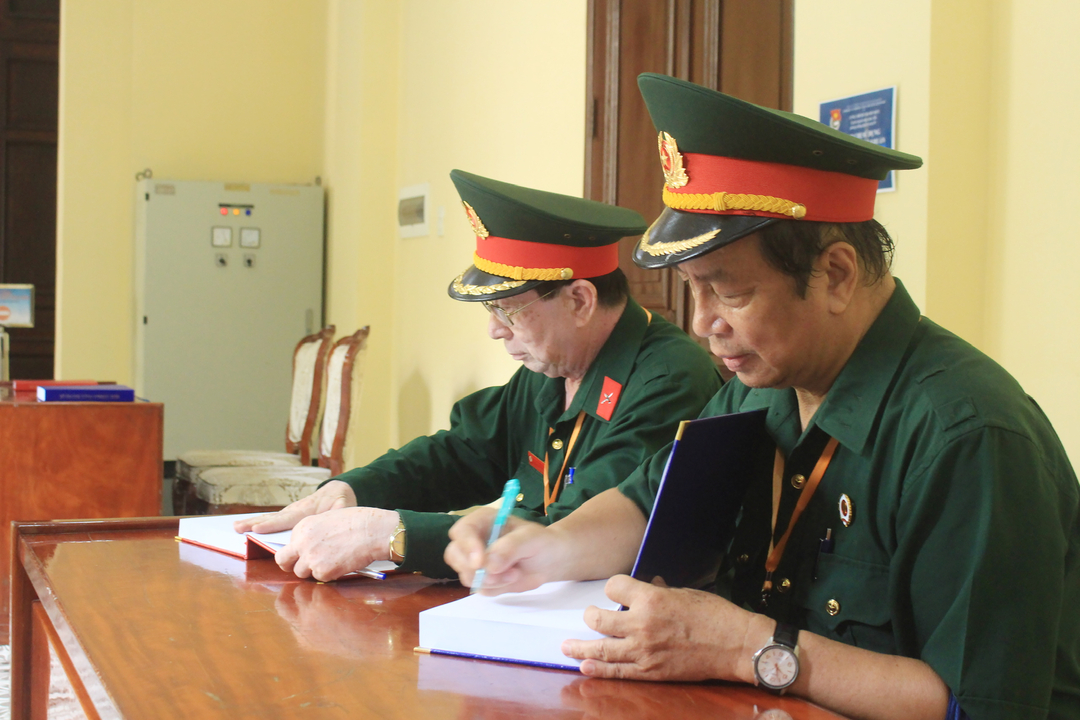 Ông Trần Văn Thiện, Cựu chiến binh quận 3 cùng đồng đội viết sổ lưu niệm ghi lại cảm nghĩ sau khi tham quan trụ sở UBND, HĐND TP.HCM. Ảnh: Nguyễn Thủy.