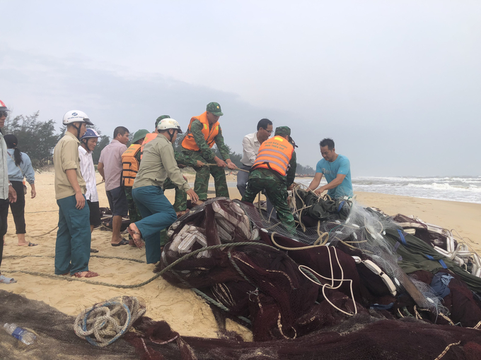 Các lực lượng chức năng và chính quyền địa phương hỗ trợ ngư dân đưa ngư lưới cụ lên bờ. Ảnh: BPH.