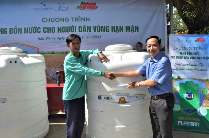 Ông Nguyễn Ngọc Thắng, Trưởng Văn phòng đại diện Báo Nông nghiệp Việt Nam khu vực ĐBSCL (bên phải) trao bồn nước cho người dân.