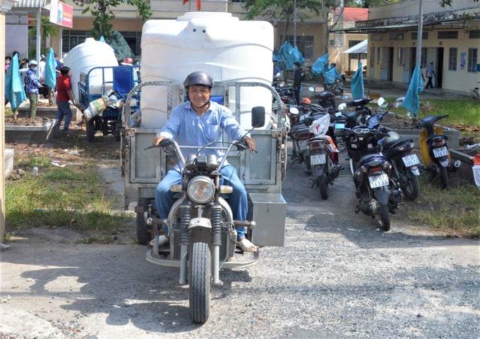 Do bồn chứa nước to, người dân không thể tự chở về nhà bằng xe máy, nên những hộ dân góp tiền thuê xe 3 bánh chở về tận nhà. Ảnh: Trung Chánh.