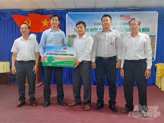 Đại điện nhà tài trợ Tập đoàn Tân Á Đại Thành trao bảng tượng trưng tặng 30 bồn nước cho 30 hộ dân có hoàn cảnh khó khăn. Ảnh: Minh Đảm.