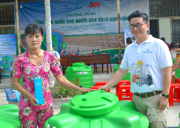 Ông Nguyễn Thành Hiệp, Phó Tổng Giám đốc Tổng công ty HUD - Tập đoàn Tân Á Đại Thành trao quà tặng và bồn chứa nước cho người dân. Ảnh: Minh Đảm.