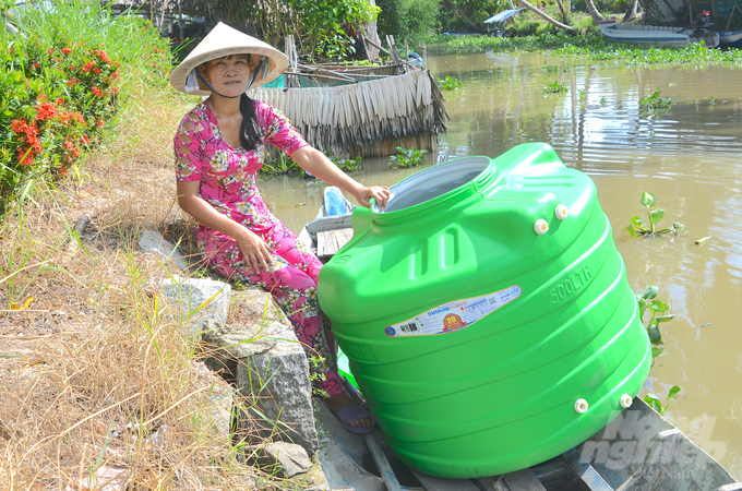 Người dân dùng xuồng ba lá vận chuyển bồn nước về nhà. Ảnh: Minh Đảm.