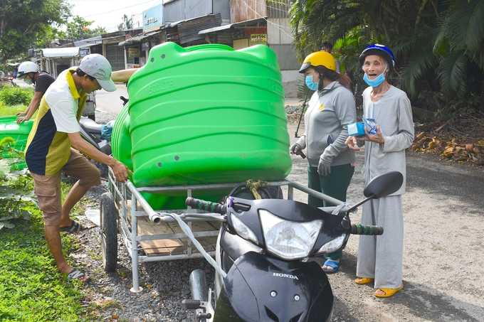 Hai hộ dân tự chế chiếc xe kéo mang bồn nước về nhà. Ảnh: Minh Đảm.