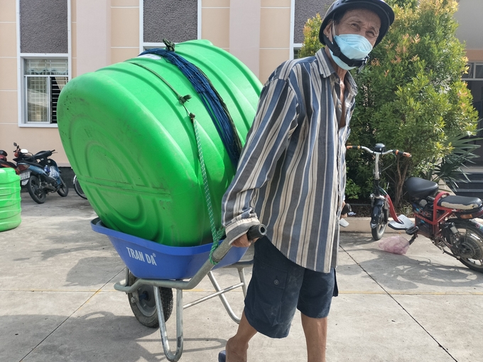 Một hộ dân ở gần địa điểm nhận hỗ trợ dùng xe kéo bồn nước về nhà. Ảnh: Minh Đảm.