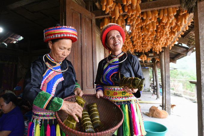 Phụ nữ người Dao Quế Lâm giới thiệu bánh chưng đen với du khách. Ảnh: Tùng Đinh.