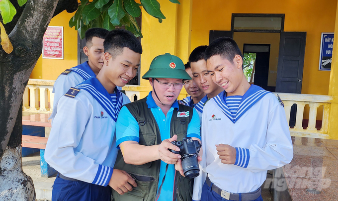 Các chiến sĩ trẻ trên đảo rất vui được ngắm nhìn những tấm hình do nhà báo Minh Sáng chụp tại đảo. Ảnh: Ngô Xuân Chinh. 
