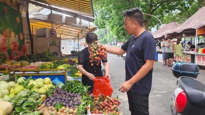 Customers buy Vietnamese lychees from Ma Tieu Hoa, a fruit stall owner at Pingxiang Food Street, Guangxi, China. Photo: Van Viet.