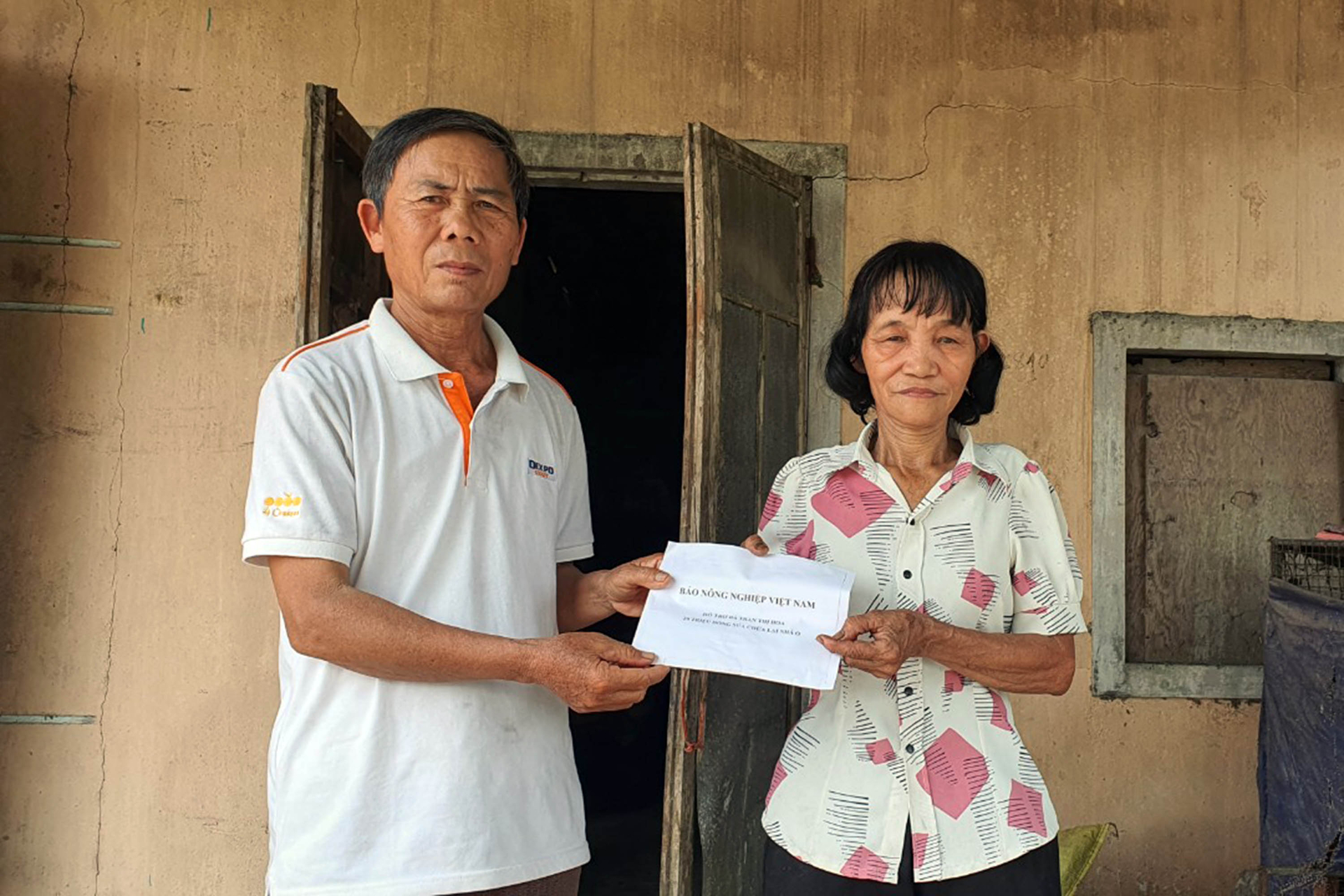 Trao kinh phí hỗ trợ hỗ trợ sửa chữa nhà cho bà Trần Thị Hoa. Ảnh: Phan Khiêm.