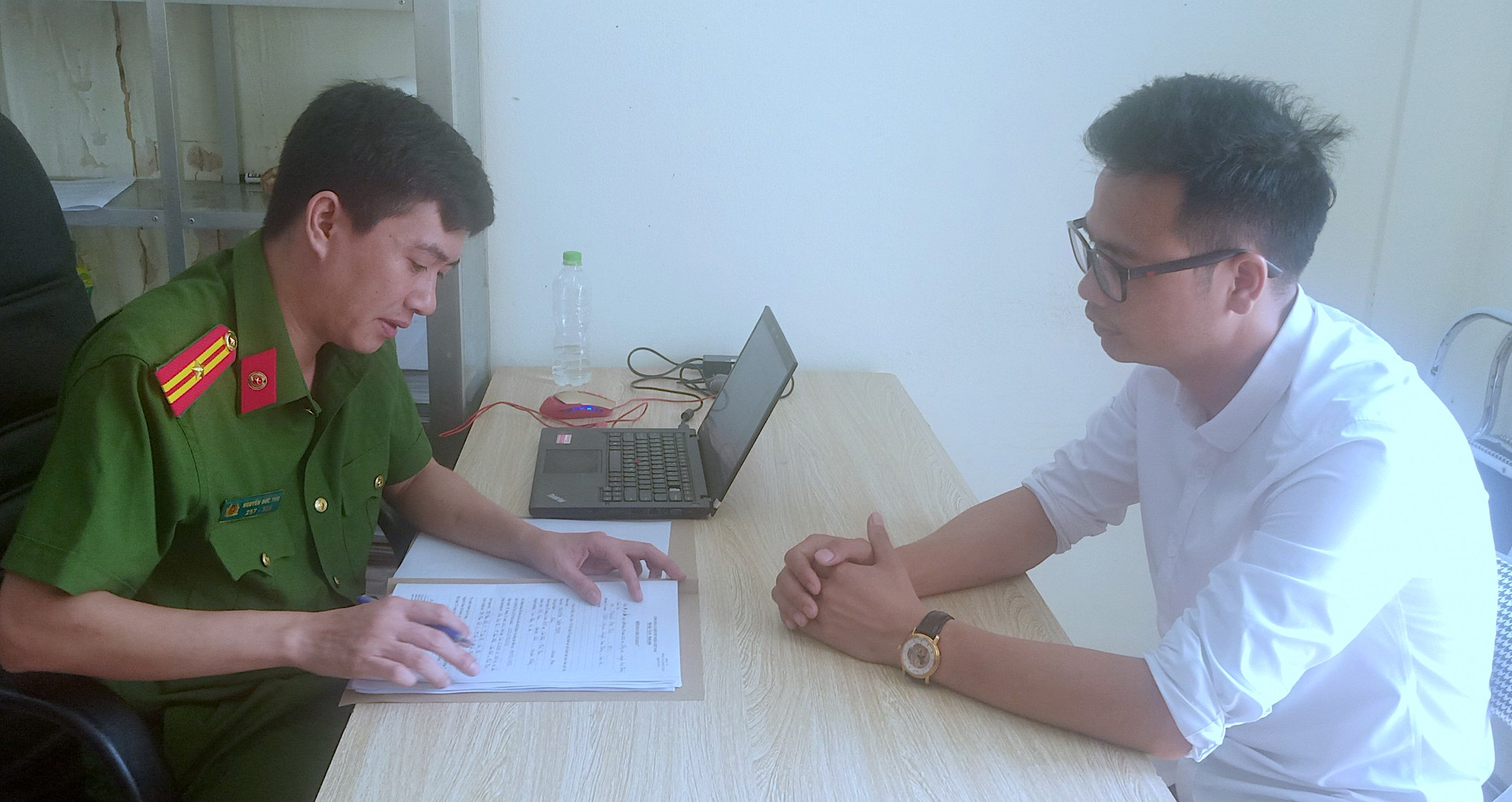 Đối tượng Nguyễn Tuấn Minh (phải) làm việc tại cơ quan công an về việc sử dụng giấy chứng nhận quyền sử dụng đất giả để giao dịch.