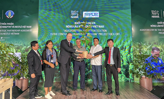 Ông Mark Schneider, Giám đốc điều hành Tập đoàn Nestlé (thứ 3 từ trái sang) trao cây đến người nông dân (thứ 4 từ trái sang), khởi động dự án Nông lâm kết hợp tại Việt Nam.