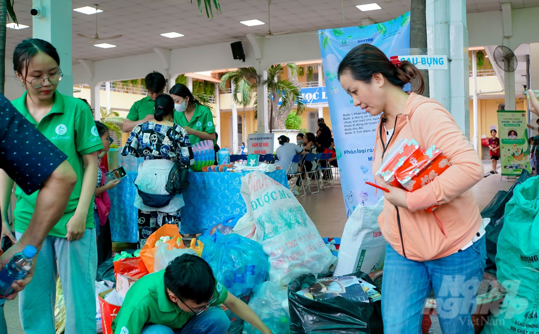 Chị Phạm Thị Hồng Ngọc (quận 12, TP.HCM) cùng bé Trần Phạm Nhật Đức (15 tuổi) chuẩn bị giấy vụn, rác thải để đổi lấy quà là các sản phẩm gia dụng tại 'Ngày hội tuổi thơ'.