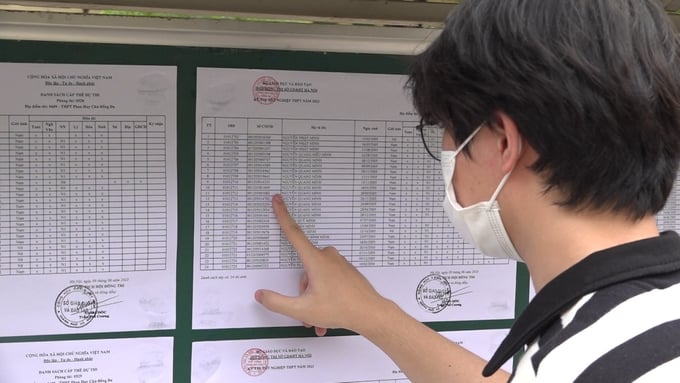Một thí sinh tìm tên, phòng thi và số báo danh được niêm yết tại điểm thi trường THPT Phan Huy Chú (phường Đống Đa, Hà Nội). Ảnh: Hùng Khang.