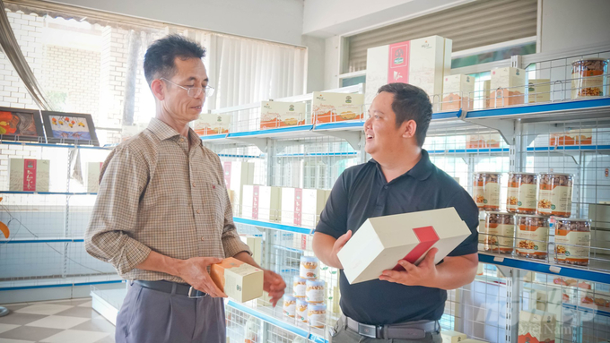 Mr. Tran Van Tuyen (left) introduced the reporter of Vietnam Agriculture News about the candy cashew products from My Le Co., Ltd. Photo: Tran Trung.