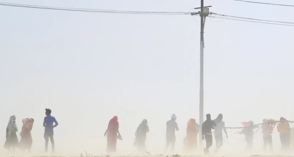 People walk through a dust storm in Prayagraj, India. Countries across the world are experiencing record temperatures. Photograph: Sanjay Kanojia/AFP/Getty Images