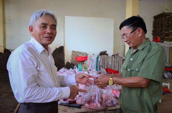 Ông Hồ Sỹ Quảng (phải) trao túi thịt cho khách đến ăn cỗ. Ảnh: Dương Đình Tường.