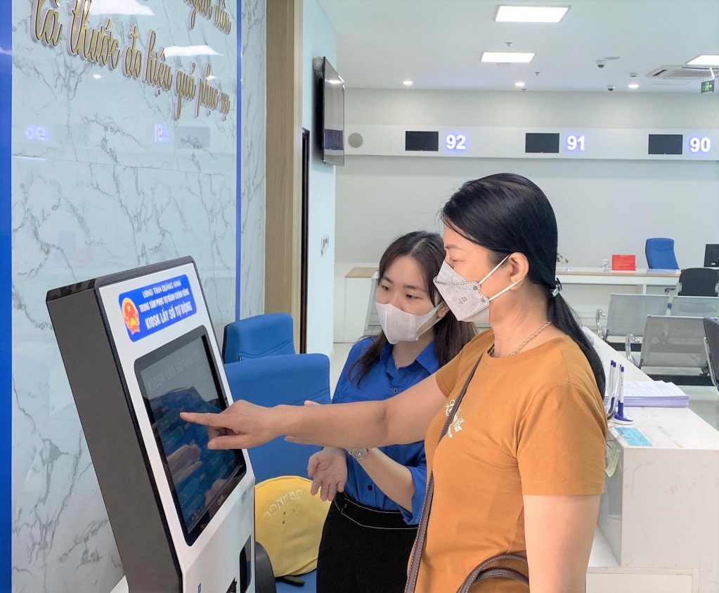 Cán bộ Trung tâm Phục vụ hành chính công tỉnh Quảng Ninh hỗ trợ người dân sử dụng các tiện ích của hệ thống Chính quyền điện tử tỉnh. Ảnh: Minh Đức