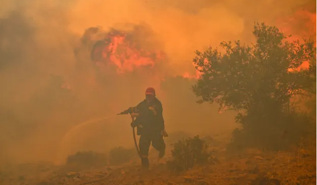 A firefighter runs as he tries to control a wildfire in New Peramos, Greece, as extreme heat grips much of Europe including Italy and Spain. Photograph: AFP/Getty Images