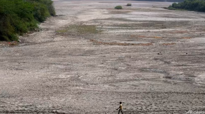 A man walks across an almost dried up bed of river Yamuna amid hot weather in New Delhi, India, May 2, 2022. Photo: AP/Manish Swarup