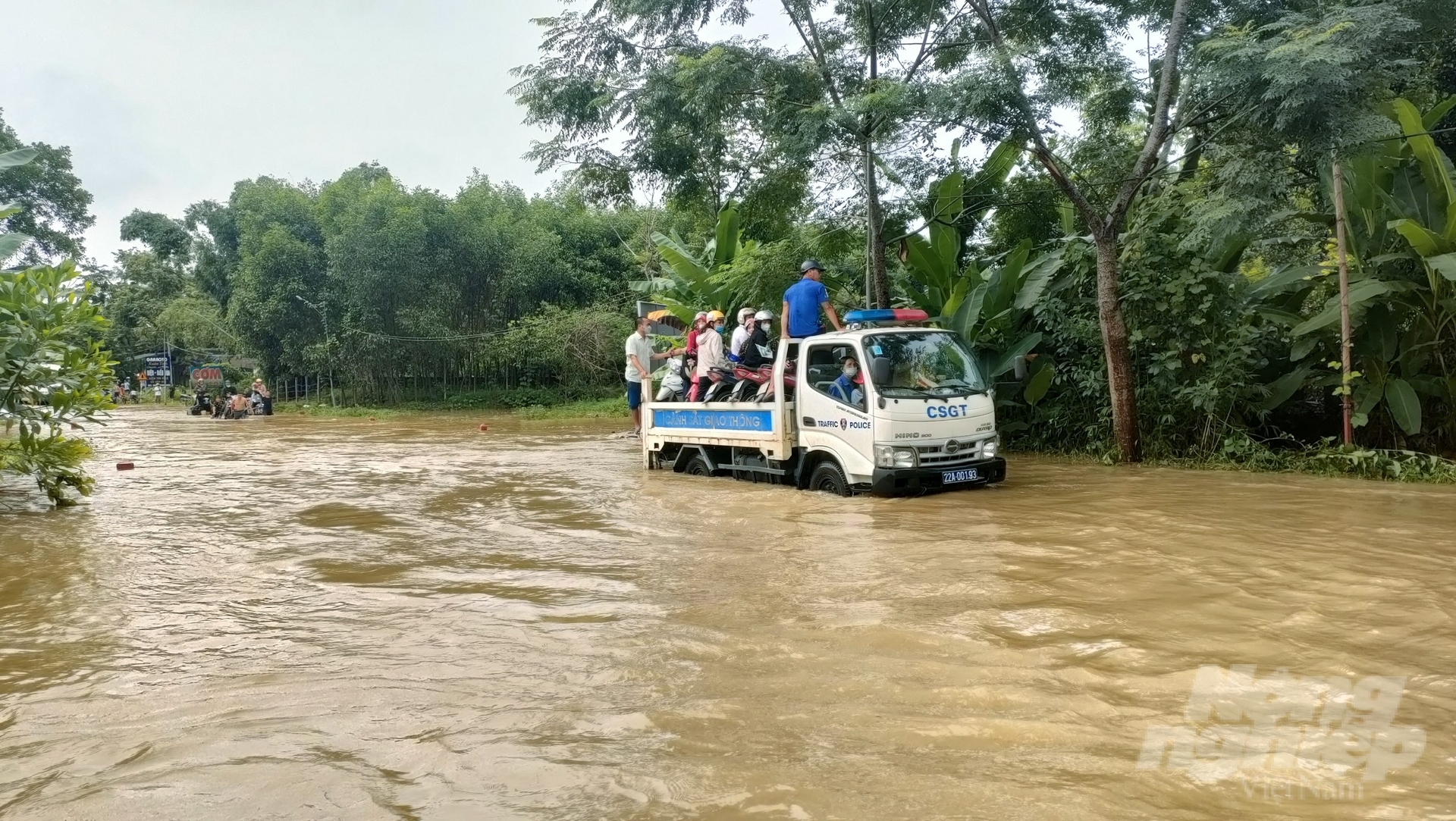 Lực lượng chức năng huyện Hàm Yên huy động phương tiện hỗ trợ người dân vượt qua dòng nước lũ. 
