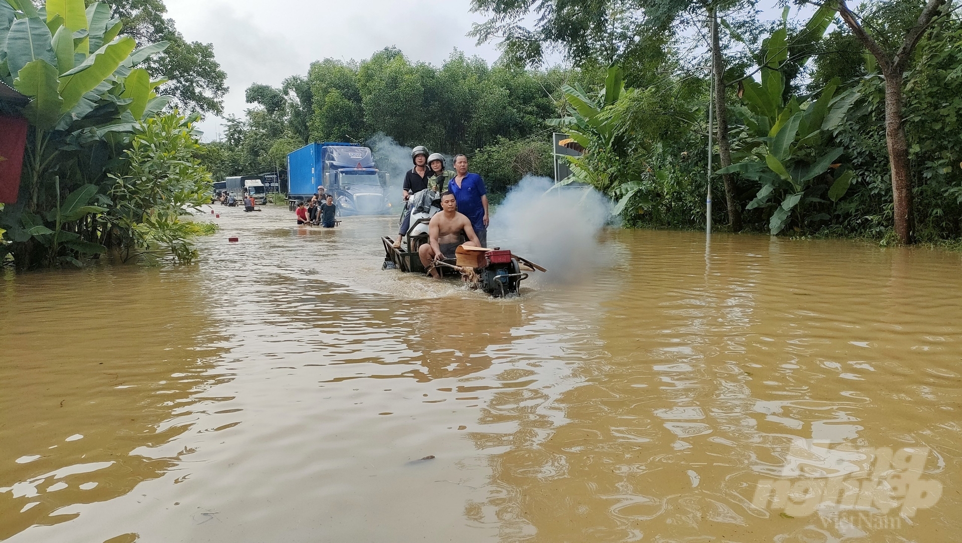 Người dân địa phương hỗ trợ người tham gia giao thông qua dòng nước bị ngập úng do mưa lớn tại Quốc lộ 2C.
