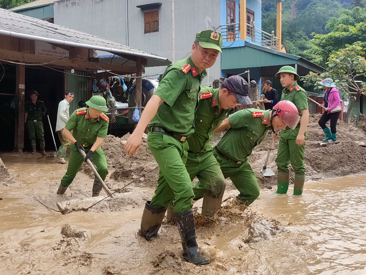 Lực lượng công an hỗ trợ người dân dọn dẹp bùn đất tràn vào nhà trong đợt mưa lũ vừa qua. Ảnh: Văn Đức.