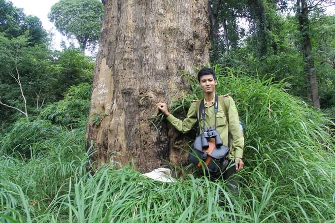 Forest ranger Pham Duc Huy with a forest kit including a camera and binoculars.